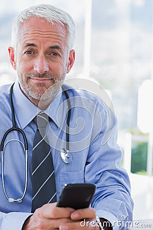 Attractive doctor using his smartphone Stock Photo