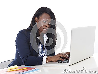 Attractive and efficient black ethnicity woman sitting at office computer laptop desk typing Stock Photo