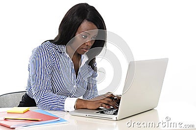 Attractive and efficient black ethnicity woman sitting at office computer laptop desk typing Stock Photo