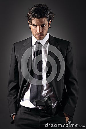 Attractive and elegant man posing with a gun in his trousers Stock Photo