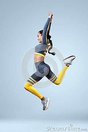 Attractive excited fitness girl dancer in sportwear jumping of joy isolated over gray background Stock Photo