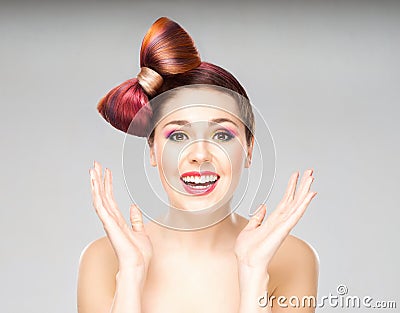 Attractive excited woman with a bow haircut and colorful make-up on grey background Stock Photo