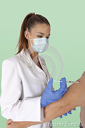 Attractive female doctor with virus protection mask and latex gloves injecting vaccine into patient Stock Photo