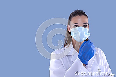 Attractive female doctor with virus protection mask and latex gloves looking straight ahead and blue background Stock Photo