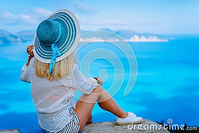 Attractive female tourist with turquoise sun hat enjoying amazing azure seascape, Greece. Cloudscape shadows on the sea Stock Photo