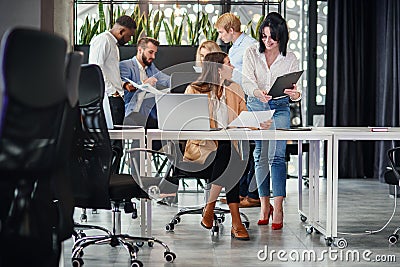 Attractive worker consulting with her office manager and signing financial document at her workplace. Stock Photo