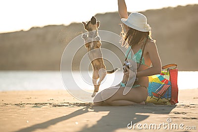 Attractive fit trendy modern hipster woman playing with straw puppy dog on beach Stock Photo