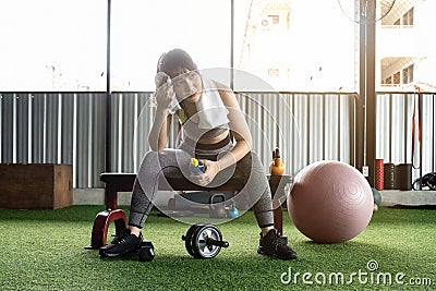 Attractive fitness woman sitting on a chair and resting after workout at fitness centre. Female take a break after hard Stock Photo