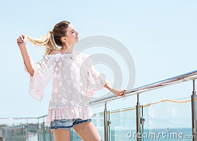 An attractive girl is enjoying summer and looking happy. Charming young model girl on a bright blue sky background. Stock Photo