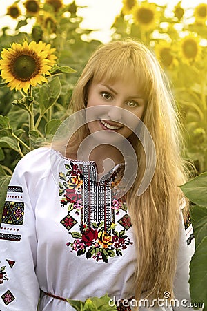 Girl with long hair in Ukrainian clother posing among the bales in the field Stock Photo