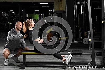 Attractive girl with a personal trainer working out in a gym. Fitness instructor conducts personal training Stock Photo