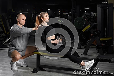 Attractive girl with a personal trainer working out in a gym. Fitness instructor conducts personal training Stock Photo