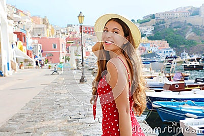 Attractive girl in Procida, Italy. Beautiful fashion woman with polka dots red dress and hat walks along the harbor of Procida Stock Photo