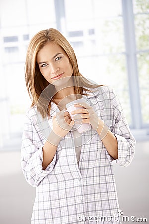 Attractive girl in pyjama drinking tea smiling Stock Photo