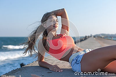 Attractive girl in short tank top and shorts on seafront Stock Photo