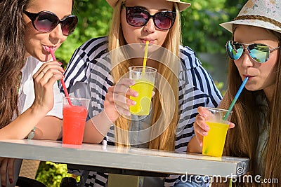 Attractive girlfriends enjoying cocktails in an outdoor cafe, friendship concept Stock Photo