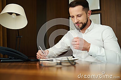 Attractive handsome successful confident caucasian businessman, journalist, businessman on business trip, writes and makes notes Stock Photo