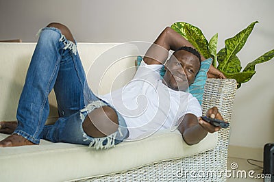 Attractive and happy black African American man relaxed at home sofa couch enjoying watching television sports or movie smiling Stock Photo