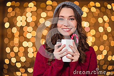 Attractive happy curly young woman drinking coffee with candy cane Stock Photo