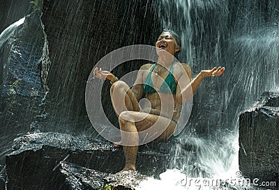 Attractive and happy mid adult woman with grey hair 40s or 50s enjoying blissful and free at beautiful tropical waterfall feeling Stock Photo