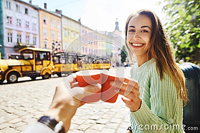 Attractive happy smiling woman sitting in the center of old city with paper cup of coffee Stock Photo