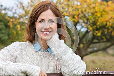 Attractive Happy Middle Aged Woman Resting on Fence Stock Photo