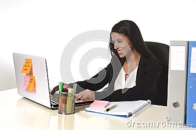 Attractive hispanic businesswoman sitting at office desk working on computer laptop smiling happy Stock Photo