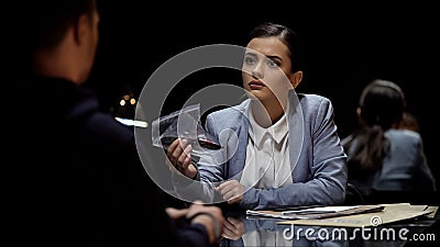 Attractive lady interrogator demonstrating bloody knife evidence to suspect Stock Photo