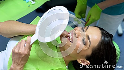 Attractive lady looking at result of sealant placement, cosmetic dentistry Stock Photo