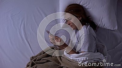 Attractive lady lying in bed and chatting in social networks with boyfriend Stock Photo