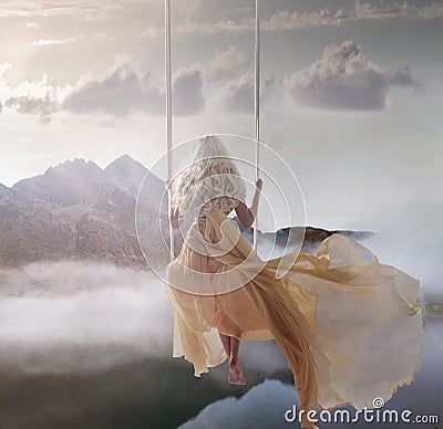 Attractive lady sitting on the swing above the calm lake Stock Photo