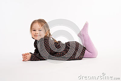 Attractive little child in dress liying on the floor and looking at the camera isolated over white background Stock Photo