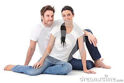 Attractive loving couple sitting on floor smiling Stock Photo