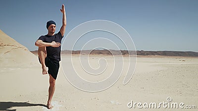 Attractive male doing yoga utthita hasta padangusthasana on a rock in desert Stock Photo