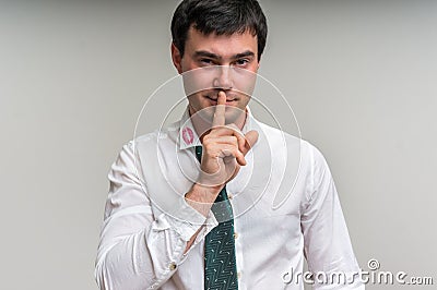 Attractive man with finger on lips and lipstick on shirt collar Stock Photo