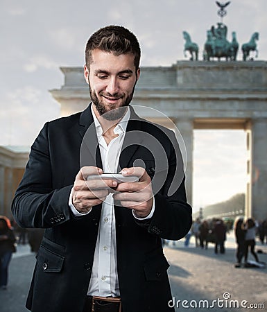 Attractive man plays with his smart phone in front of the Brandenburger Gate Stock Photo