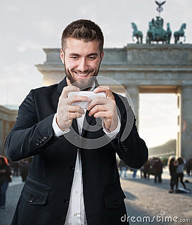 Attractive man plays with his smart phone in front of the Brandenburger Gate Stock Photo