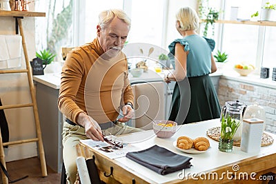 Attractive man sitting while his spouse cooking at the kitchen Stock Photo