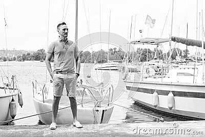 Attractive man stands at the nose of a boats on pier at river marina Stock Photo