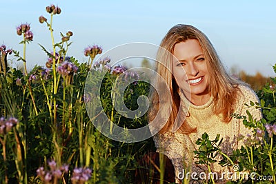 Attractive middle age woman sitting in a lilac flower field Stock Photo