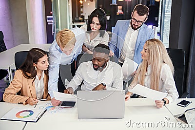 Attractive multiracial office managers discussing their business plan on the personal computer and analyse issues. Stock Photo