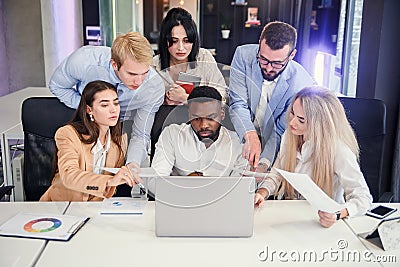 Attractive multiracial office managers discussing their business plan on the personal computer and analyse issues. Stock Photo