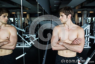 Attractive muscular man admiring his muscles in mirror and checking workout results. Summer Ready Beach Body. Sport, training moti Stock Photo