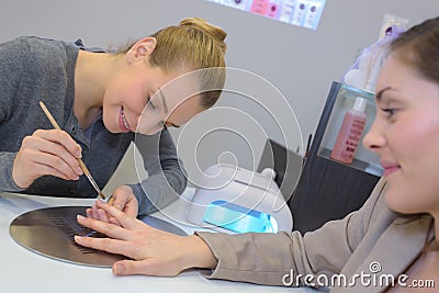 Attractive nail salon worker giving manicure to customers Stock Photo