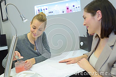 Attractive nail salon worker giving manicure to one customers Stock Photo