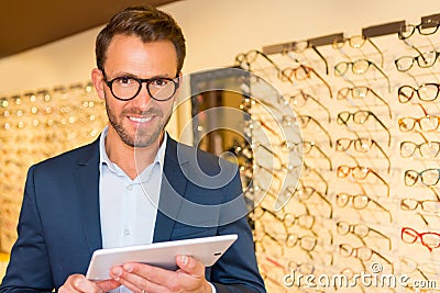 Attractive optician working with tablet in his glasses shop Stock Photo