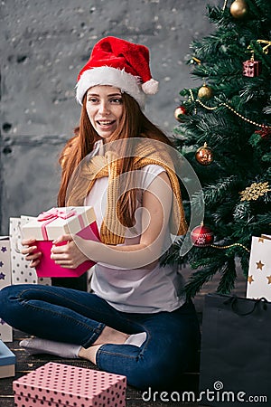 Attractive pleasant ginger girl holding a present from Santa Stock Photo