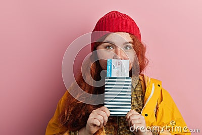 Attractive pleasant ginger hipster girl holding ticket in front of her mouth Stock Photo