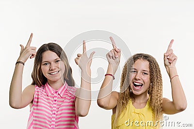 Attractive positive two teenage girl pointing her index finger up Stock Photo