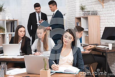 Attractive pregnant girl is working in office with colleagues. Pregnant businesswoman in workspace. Maternity. Stock Photo